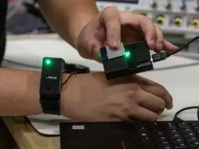 A RESEARCHER TRANSFERS INFORMATION FROM A CHIP IN A WATCH BY TOUCHING A SENSOR CONNECTED TO A LAPTOP